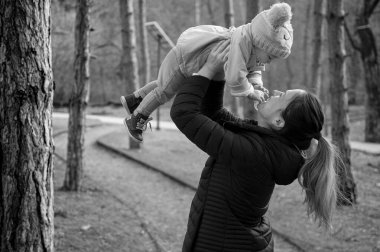 Mutlu genç anne, tatlı kızını havaya kaldırıyor. 