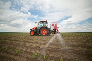 Traktör tarlada böcek ilacı kimyasallarıyla gübreleme yapıyor. 
