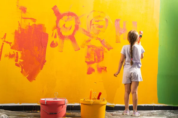 A girl draw with a brush on the wall in the house