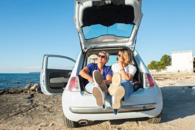 Adriyatik kıyısında bir Fiat 500 'ün bagajında iki kadın oturuyor ve eğleniyorlar. Umag, Istrian Yarımadası, Hırvatistan