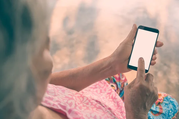 Äldre kvinna med en smarttelefon. Vintage filter. — Stockfoto