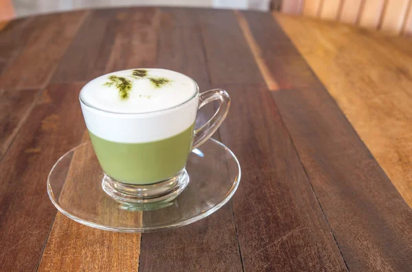 A cup of green tea matcha latte with saucer. Wood table backgrou — Stock Photo, Image