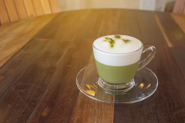 A cup of green tea matcha latte with saucer. Wood table backgrou — Stock Photo, Image