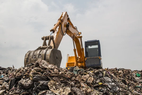 Гора мусора с работающим экскаватором — стоковое фото