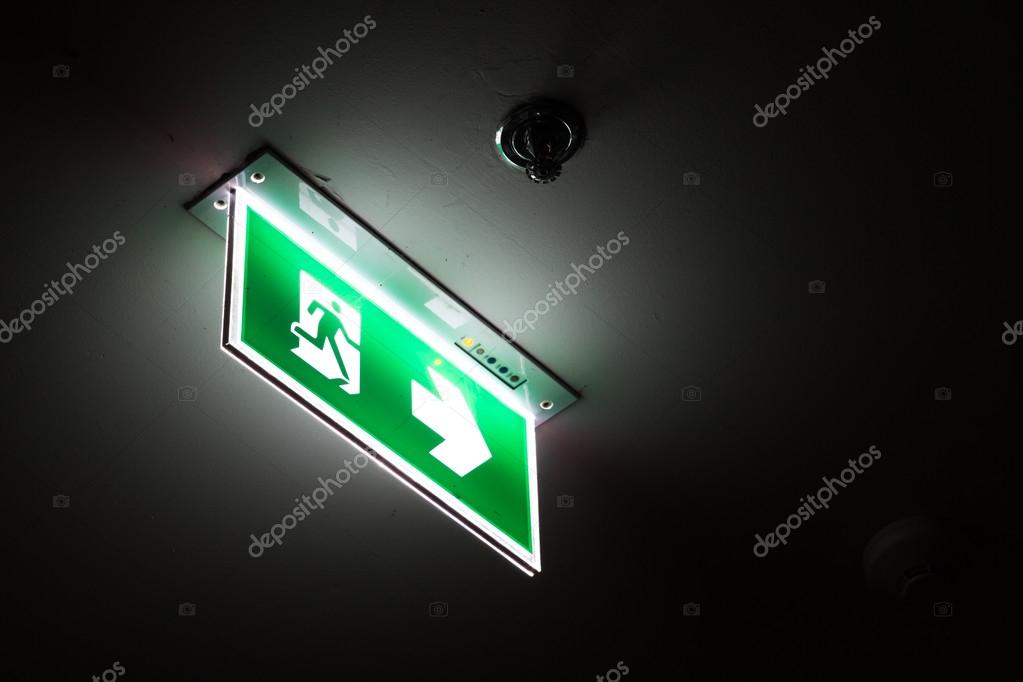 Emergency exit sign above a black doorway at night. Stock Photo by