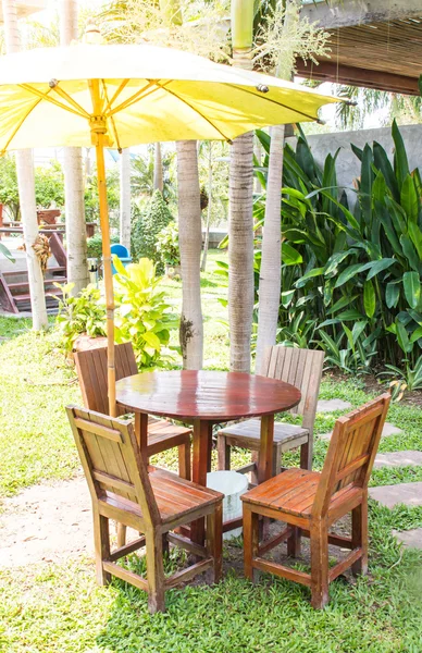 Mesa de jantar de madeira definida no jardim exuberante e luz do sol — Fotografia de Stock