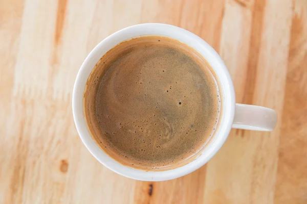 Eine Tasse Kaffee in einer weißen Tasse auf hölzernem Hintergrund — Stockfoto