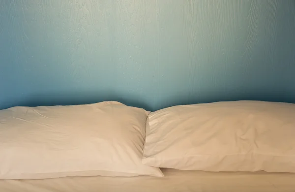 En uoppredd seng med hvitt lin bakgrunn blått tre – stockfoto