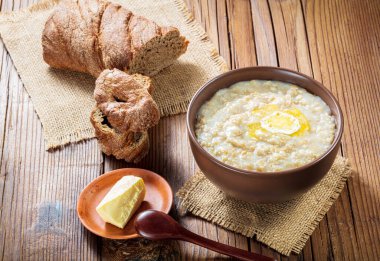 Seramik kasede yulaf ezmesi, ahşap bir tabakta ahşap kaşık ve tereyağı.