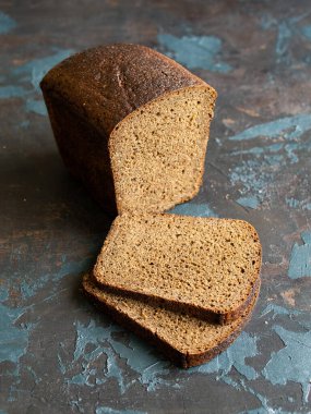 Kesme tahtasında koyu arkaplanda dilimlenmiş çavdar ekmeği. Boşluğu kopyala, kapat