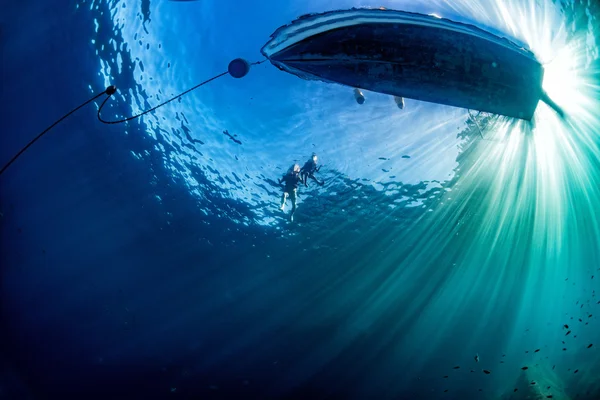 Boat ship from underwater blue ocean with sun rays — Stock Photo, Image