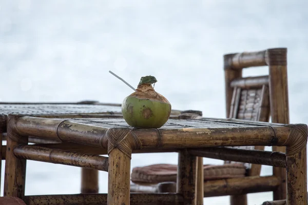 Coco fresco en la mesa de bambú en la playa — Foto de Stock