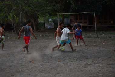 Gili Asahan, Endonezya - Ağustos, 22 2016 - çocuklar futbol günbatımında plaja yakın bir palmiye ağacı sahada oynayan