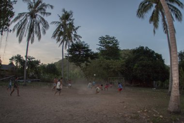 Gili Asahan, Endonezya - Ağustos, 22 2016 - çocuklar futbol günbatımında plaja yakın bir palmiye ağacı sahada oynayan