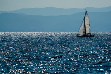 Günbatımında küçük yelkenli arka planda