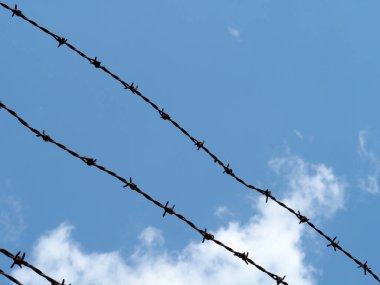 Bulutlu gökyüzü arka planında dikenli tel