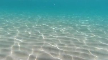 Turkuaz gölünde şnorkelle yüzerken suyun altında kum var.