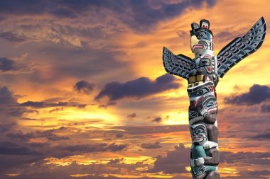 A totem wood pole in the gold cloudy background clipart