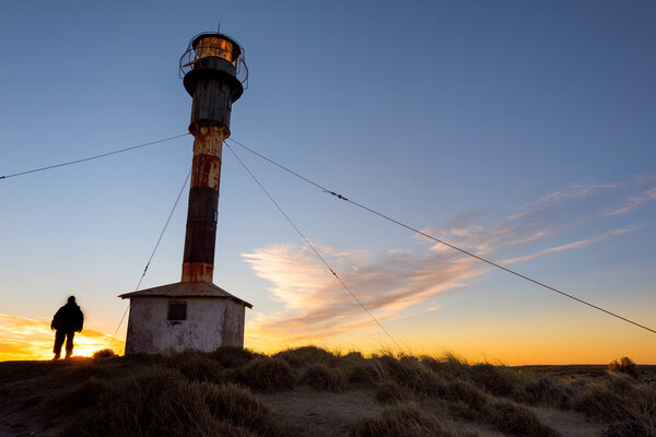 Man outside patagonia lighthouse at sunset