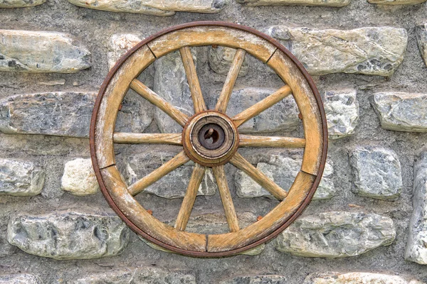 Far west wagon wheel on stone wall — Stock Photo, Image
