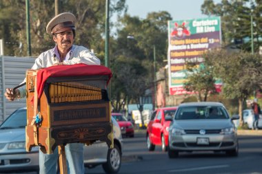 MEXICO CITY, MEXICO - FEBRUARY, 9  2015 - Poor man playing hand organ on the street clipart