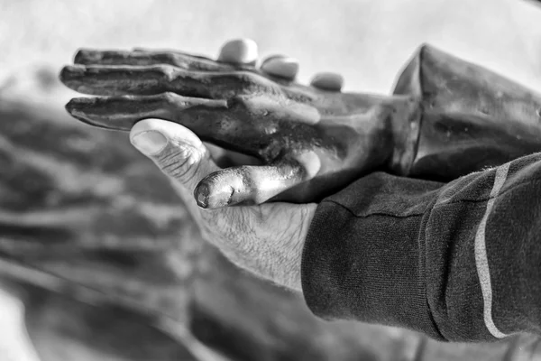 Oude man hand met koperen beeld in zwart-wit — Stockfoto