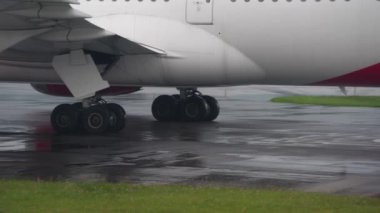 Yağmurun altında yola çıkmadan önce yolda yuvarlanan uçak tekerleğinin ayrıntıları