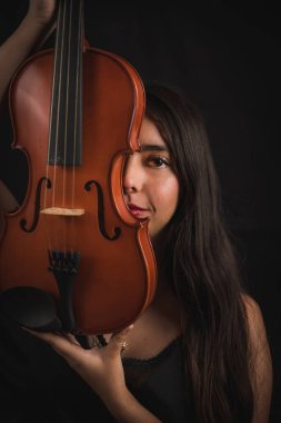 Kemanla bölünmüş genç bir İspanyol kadının yüzü, yüzünde tebessümle enstrümanın tahtasını teniyle okşarken bir gülümseme belirir.