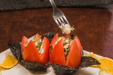 Yıldız desenli kırmızı domatesler ve deniz yosunları üzerinde sunulan balık ceviche yanında zencefil, turuncu ve yeşil zeytin, beyaz bir tabak ve ahşap zemin 7.