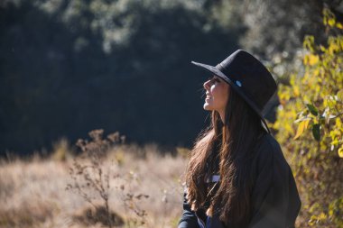 Maceracı bir kızın portresi, siyah giyinmiş, mavi bir sırt çantası, şapkası ve siyah bir sırt çantasıyla yeni yollar keşfediyor. 12