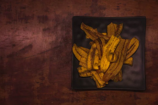 Plátanos Fritos Servidos Plato Negro Sobre Una Mesa Madera Merienda —  Fotos de Stock