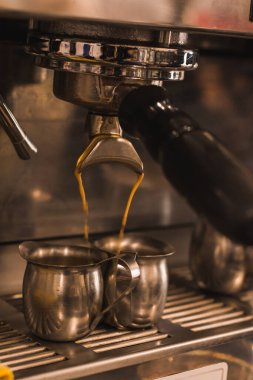 Endüstriyel kahve makinesi, çalışıyor, bir çift metal tencere üzerinde espresso servis ediyor.