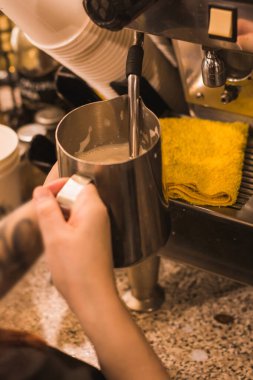 Kahveci kız kafeteryada kahve bazlı bir içecek hazırlıyor, siyah maskeler takıyor.. 