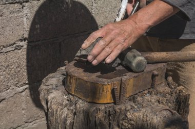 Demircide çalışan demirci, metali aletin içine sokarak keski yapmak için parlak bir metalle çalışıyor.. 
