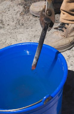 Demirci, taş oymak için keski yapmak için sudaki metali sertleştiriyor.. 