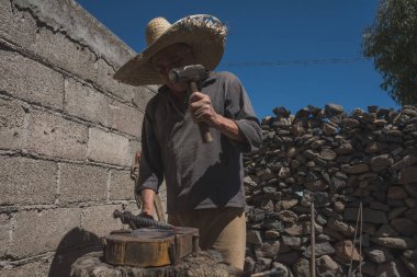 Demircide çalışan demirci, metali aletin içine sokarak keski yapmak için parlak bir metalle çalışıyor.. 