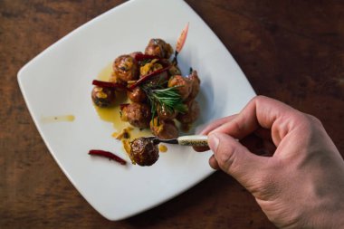 Cambray patatesleri zeytinyağı, sarımsak, biberiye ve arbol ile sotelenmiş, geleneksel Meksika yemekleri, beyaz bir tabakta ve ahşap bir arka planda..