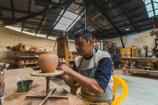 Mexican potter craftsman, working the clay with his hands in his workshop to create sculptures, vases, jugs, vases etc, using traditional methods.