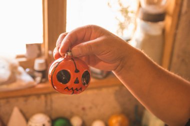 Sanatçı atölyesinde farklı renklerde Noel küreleri boyuyor, akrilik boya kullanıyor, desen ve şekil vermek için elmas boya kullanıyor..