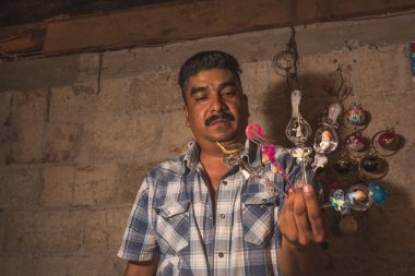 Atölyesinde yılbaşı topları yaratmak için cam üfleyen bir zanaatkar, bir kaynak makinesinin yardımıyla cam tüpleri farklı şekillerde şekillendiriyor..