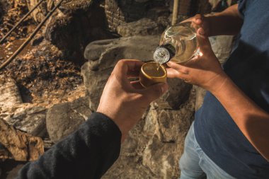 Meyveden yapılmış geleneksel kavanozları tutan erkek eller, bu kaplarda tipik Meksika içecek mezcal 'ı, ve bir başka adam da şişeden içki servisi yapıyor.. 