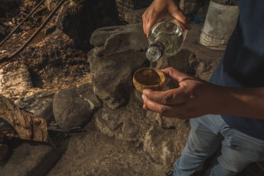 Meyveden yapılmış geleneksel kavanozları tutan erkek eller, bu kaplarda tipik Meksika içecek mezcal 'ı, ve bir başka adam da şişeden içki servisi yapıyor.. 