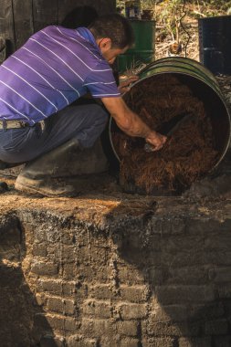 Mezcal ustası onları pişirmek için agave ananaslarının özünü döküyor ve mezcal 'ın yapıldığı suyu çıkarıyor..