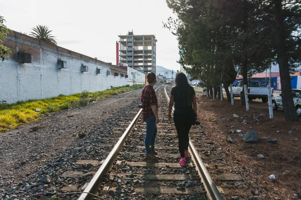 2 young women walking on the train tracks in the city