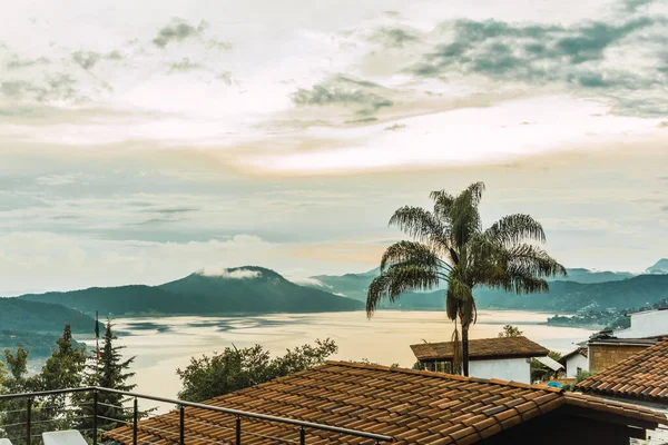 Meksika 'nın Valle de Bravo şehrinde gün batımında kulübeler ormanın ortasındaki ahşap kulübeler göl ve havuz manzarasını çok iyi tamamlıyor..