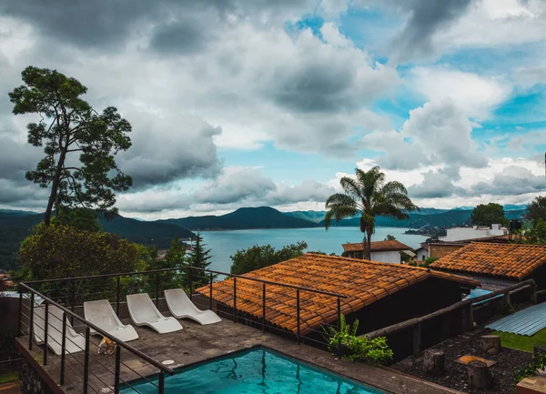 Meksika 'nın Valle de Bravo şehrinde gün batımında kulübeler ormanın ortasındaki ahşap kulübeler göl ve havuz manzarasını çok iyi tamamlıyor..