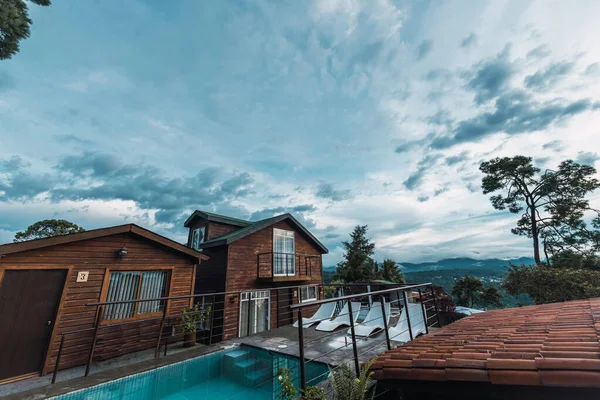 Meksika 'nın Valle de Bravo şehrinde gün batımında kulübeler ormanın ortasındaki ahşap kulübeler göl ve havuz manzarasını çok iyi tamamlıyor..