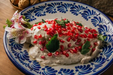 Chiles en Nogada,% 100 Meksika tarifi, ana malzemeleri bir tarafta, ceviz, kırmızı gradana gibi, ahşap bir masada Puebla talavera tabağında servis edilir..