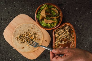 Escamoles (ant eggs) refried with tortilla chips and guacamole, traditional Mexican food of pre-Hispanic origin, served on a clay plate.