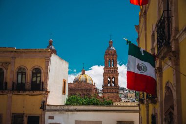 Arka planda bir kilise kulesinin ayrıntıları, Meksika bayrağı Zacatecas, Meksika şehir merkezindeki bir evden sarkıyor..